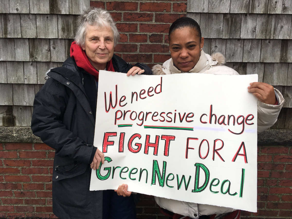 photo of two people holding a sign that says We need progressive change fight for a Green New Deal